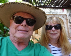Selfie with George and Sandy. George is wearing a large, straw hat, sunglasses, and green V-neck tee. Sandy has her long hair down and is wearing sunglasses and a striped top.